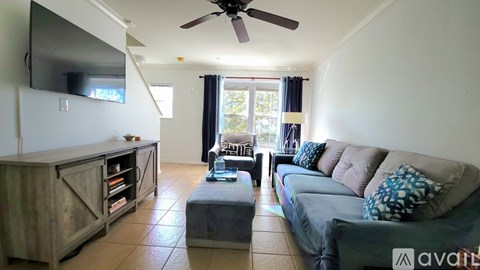 A living room with a grey couch and a wooden entertainment unit.