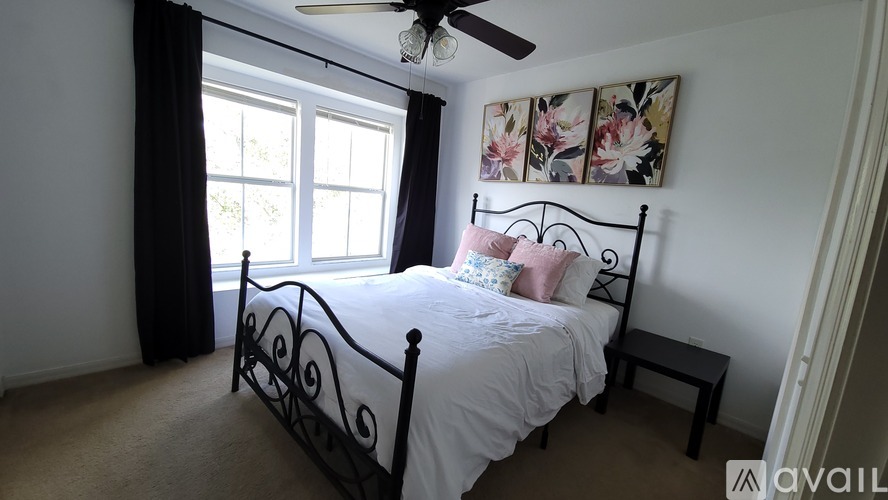A bedroom with a black metal bed frame and a ceiling fan.