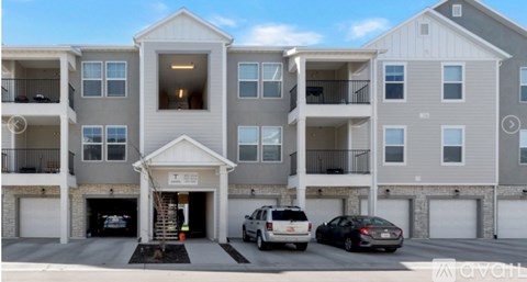 A row of townhouses with garages and cars parked in front.