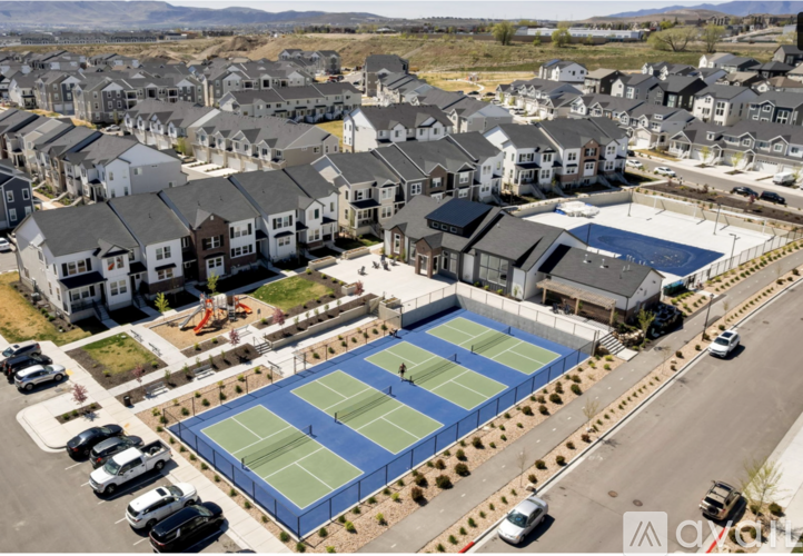 A tennis court is surrounded by a parking lot and residential buildings.