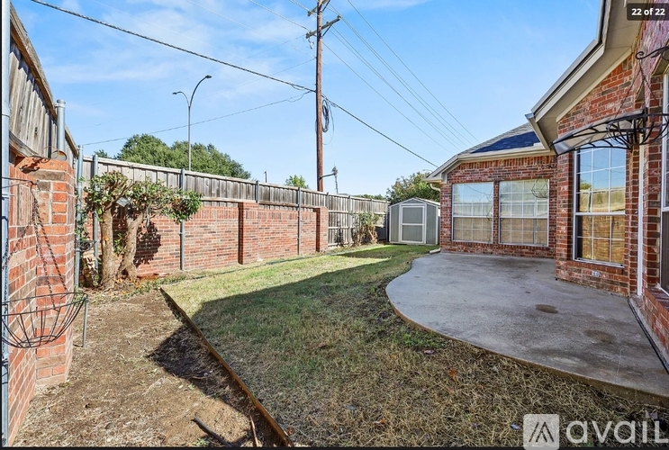 A backyard with a fence and a small building in the distance.
