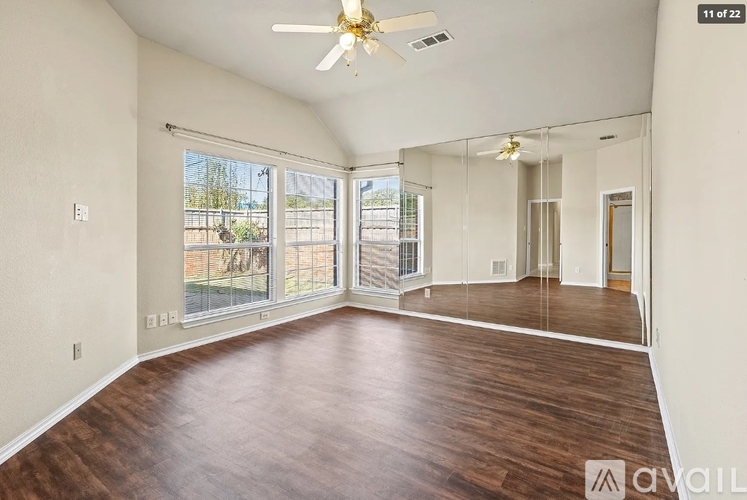 A spacious room with wood flooring and a ceiling fan.