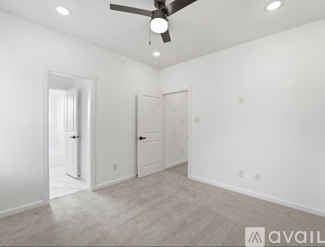 A spacious room with a ceiling fan and two doors.