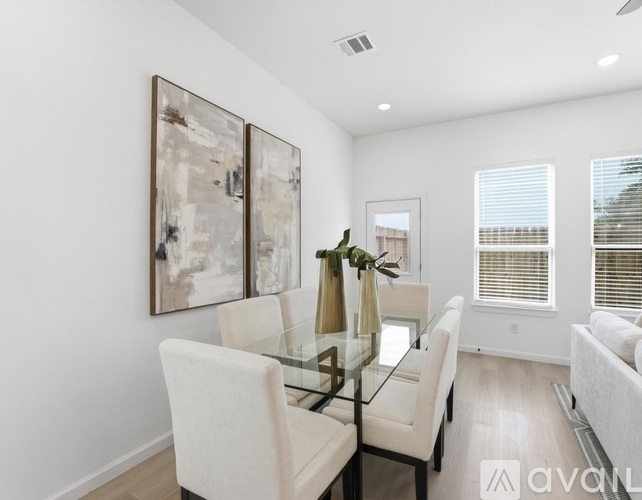 A modern dining room with a glass table and chairs.