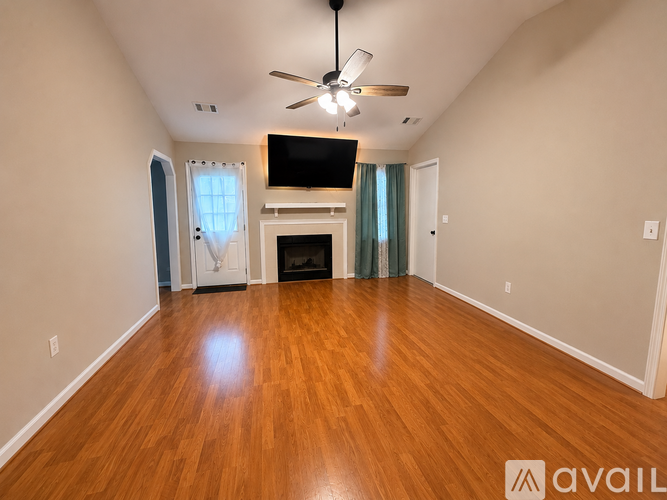A spacious room with wood flooring and a ceiling fan.