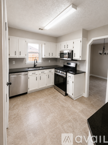 A kitchen with white cabinets and black countertops.