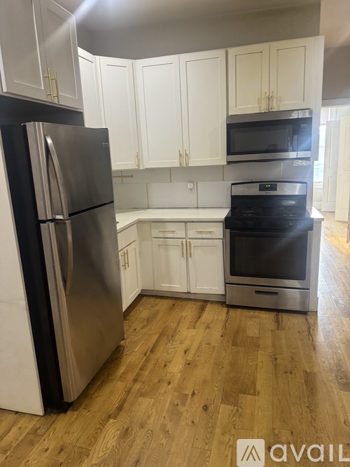 A kitchen with a black fridge and stove top oven.