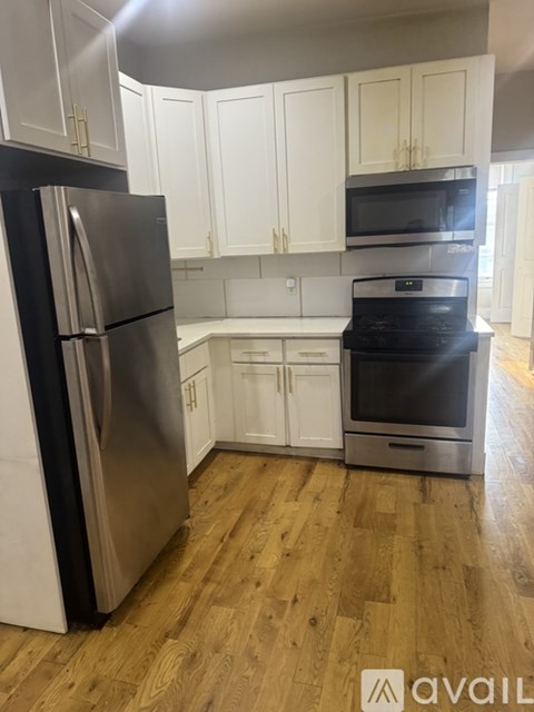 A kitchen with a black fridge and stove top oven.