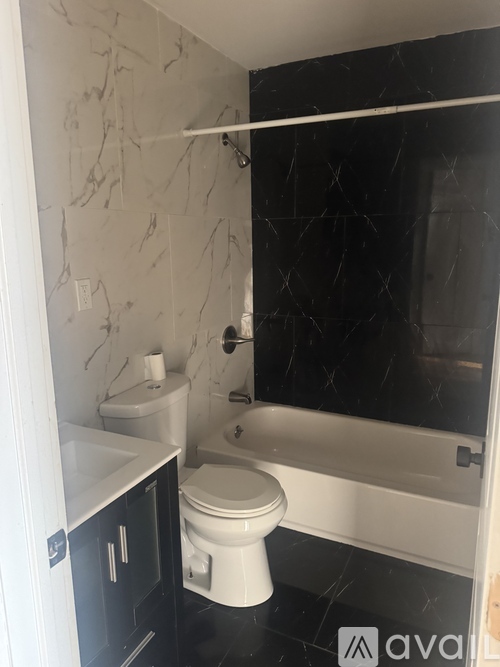 A white toilet sits in a bathroom with black marble floors and walls.