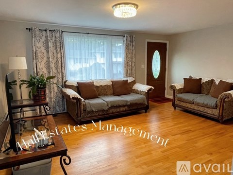 A living room with a couch, chair, and a table with a lamp on it.