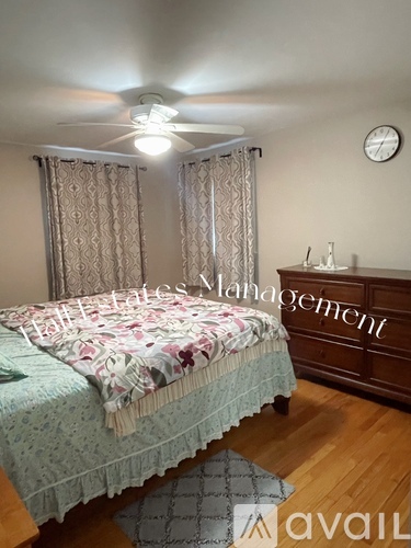 A bedroom with a bed, a dresser, and a ceiling fan.
