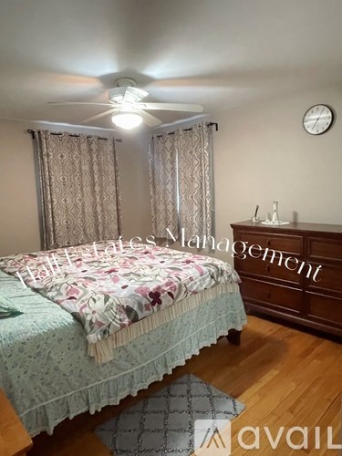 A bedroom with a bed, a dresser, and a ceiling fan.