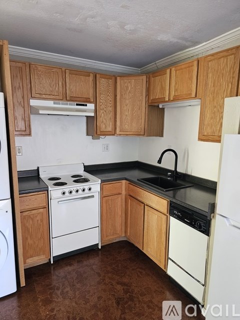 A kitchen with wooden cabinets and black countertops.