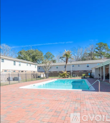 A pool surrounded by a brick patio with a building in the background.