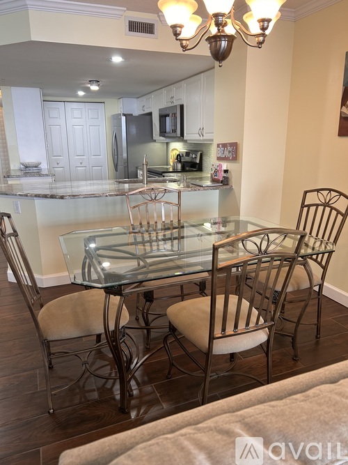 A glass dining table with four chairs in a kitchen.