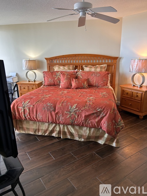 A bedroom with a large bed and a ceiling fan.