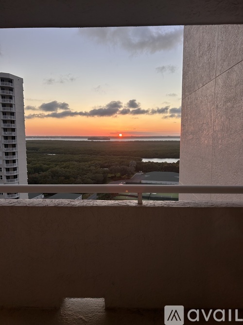 A sunset view from a balcony with a building on the left.