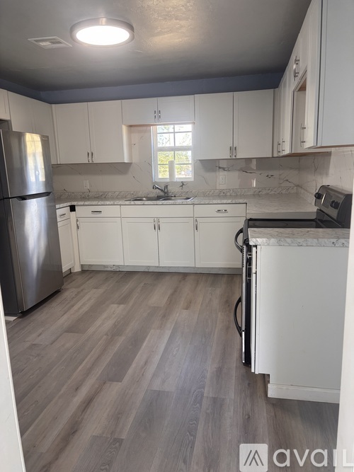 A kitchen with white cabinets and a wooden floor.