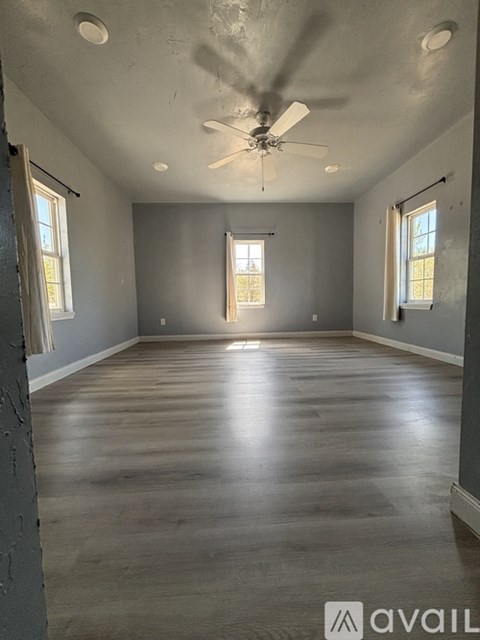 A spacious room with a ceiling fan and wooden flooring.