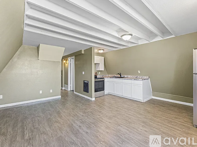 A spacious room with a kitchenette and a staircase.