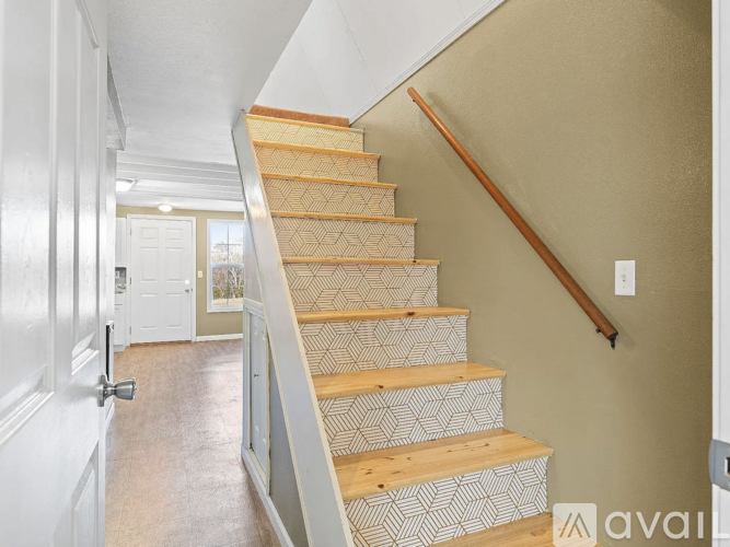 A staircase with a wooden handrail and a patterned runner.