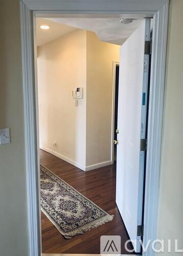 A hallway with a rug on the floor and a door on the right.