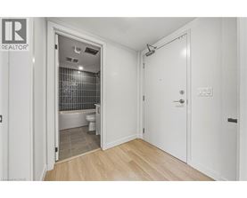 A bathroom with a toilet and a shower is visible from a hallway.