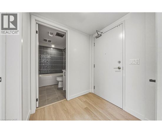 A bathroom with a toilet and a shower is visible from a hallway.