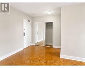 A room with a wooden floor and white walls, with a door and a glass door.