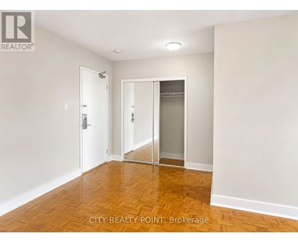 A room with a wooden floor and white walls, with a door and a glass door.