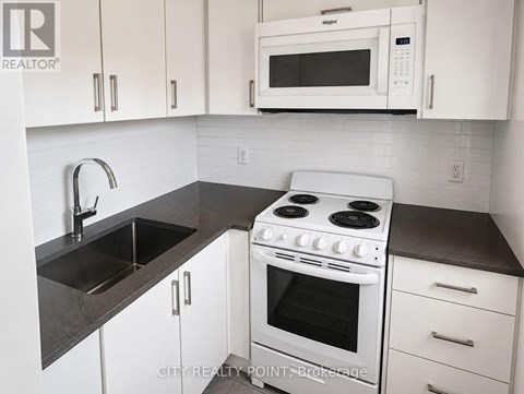 A white stove and microwave in a kitchen with white cabinets.