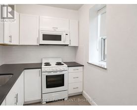 A white kitchen with a black counter top and a stove.
