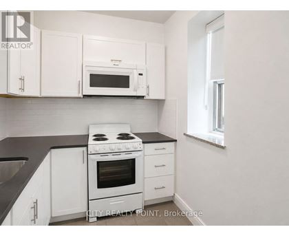 A white kitchen with a black counter top and a stove.