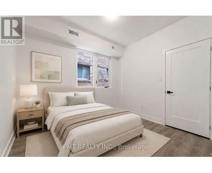A bedroom with a bed, nightstand, and window.