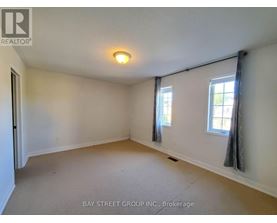 A room with a carpet floor and three windows.