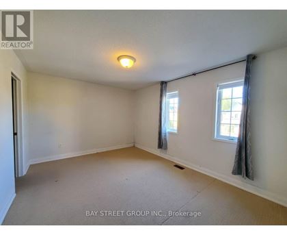 A room with a carpet floor and three windows.