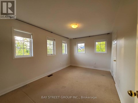 A room with a carpet floor and three windows.