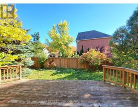 A wooden deck leads to a house with a red roof and a fence.