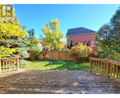 A wooden deck leads to a house with a red roof and a fence.