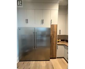 A stainless steel refrigerator in a kitchen with white cabinets.