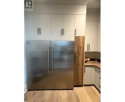 A stainless steel refrigerator in a kitchen with white cabinets.