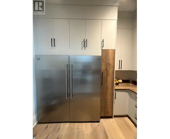 A stainless steel refrigerator in a kitchen with white cabinets.