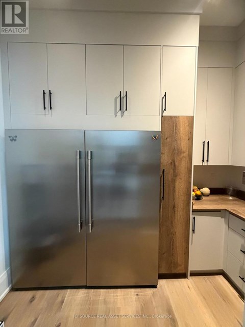 A stainless steel refrigerator in a kitchen with white cabinets.