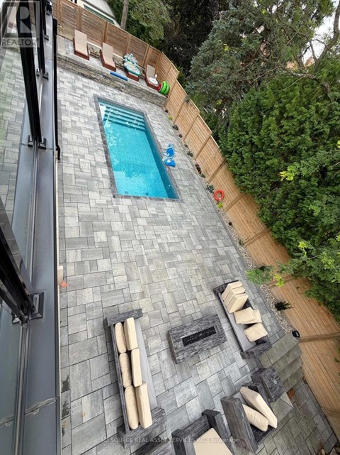 A small pool surrounded by a stone patio and wooden fence.