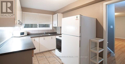 A kitchen with a refrigerator, microwave, and oven.