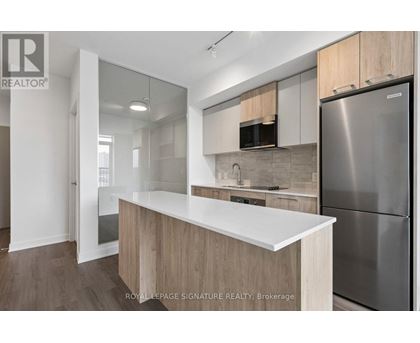 A modern kitchen with a white countertop and stainless steel appliances.