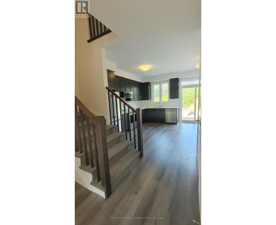 A staircase with wooden steps and a metal railing leads to a kitchen area.