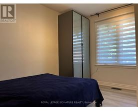 A bedroom with a bed, a window with blinds, and a sliding door.