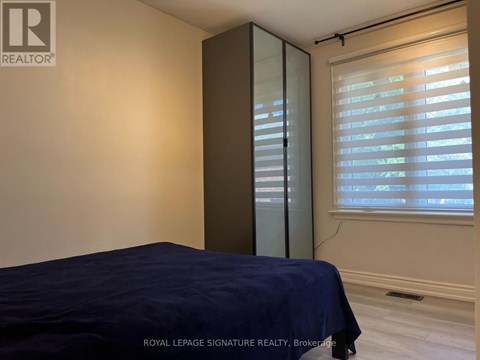 A bedroom with a bed, a window with blinds, and a sliding door.