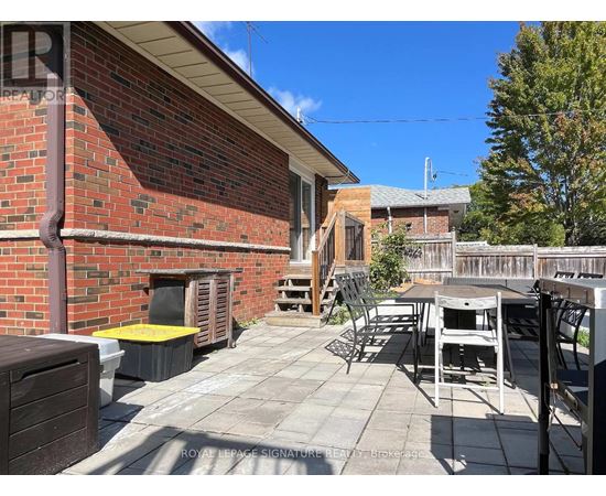 A patio with a table and chairs is in front of a brick building.